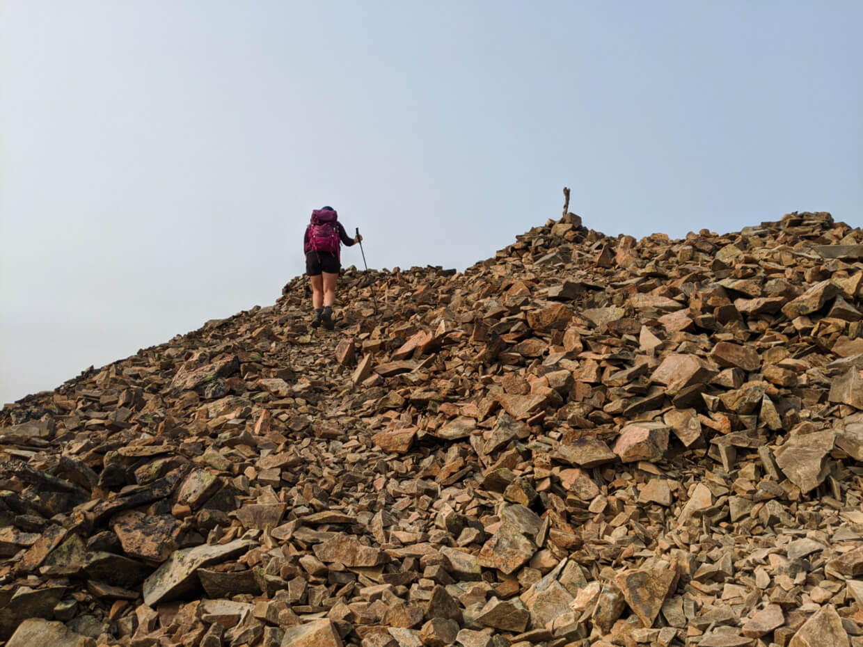 Gemma hiking through scree on Frosty Mountain ridge, almost at the summit