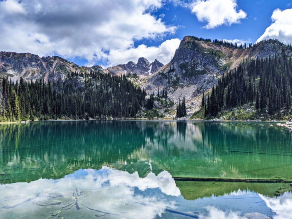 Lakeshore view of Eva Lake, an alpine lake with beautiful reflections of the surrounding mountains