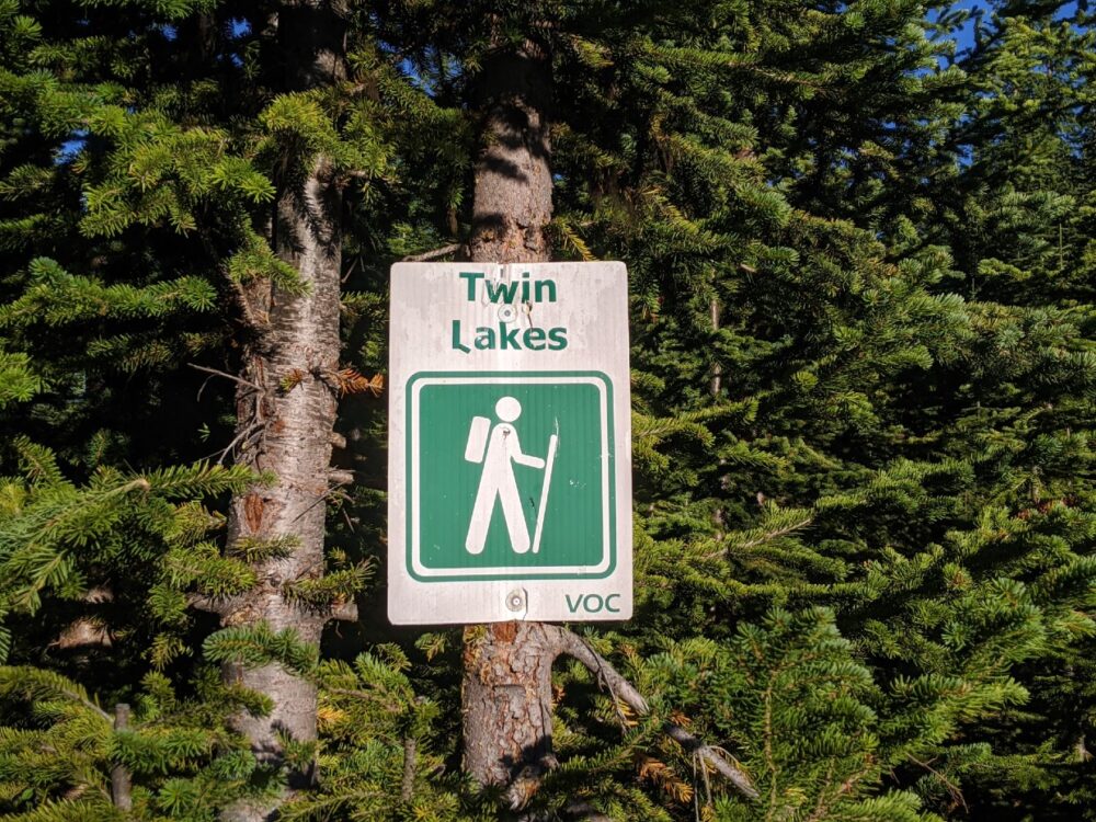 White and green Twin Lakes sign with symbol of hiker