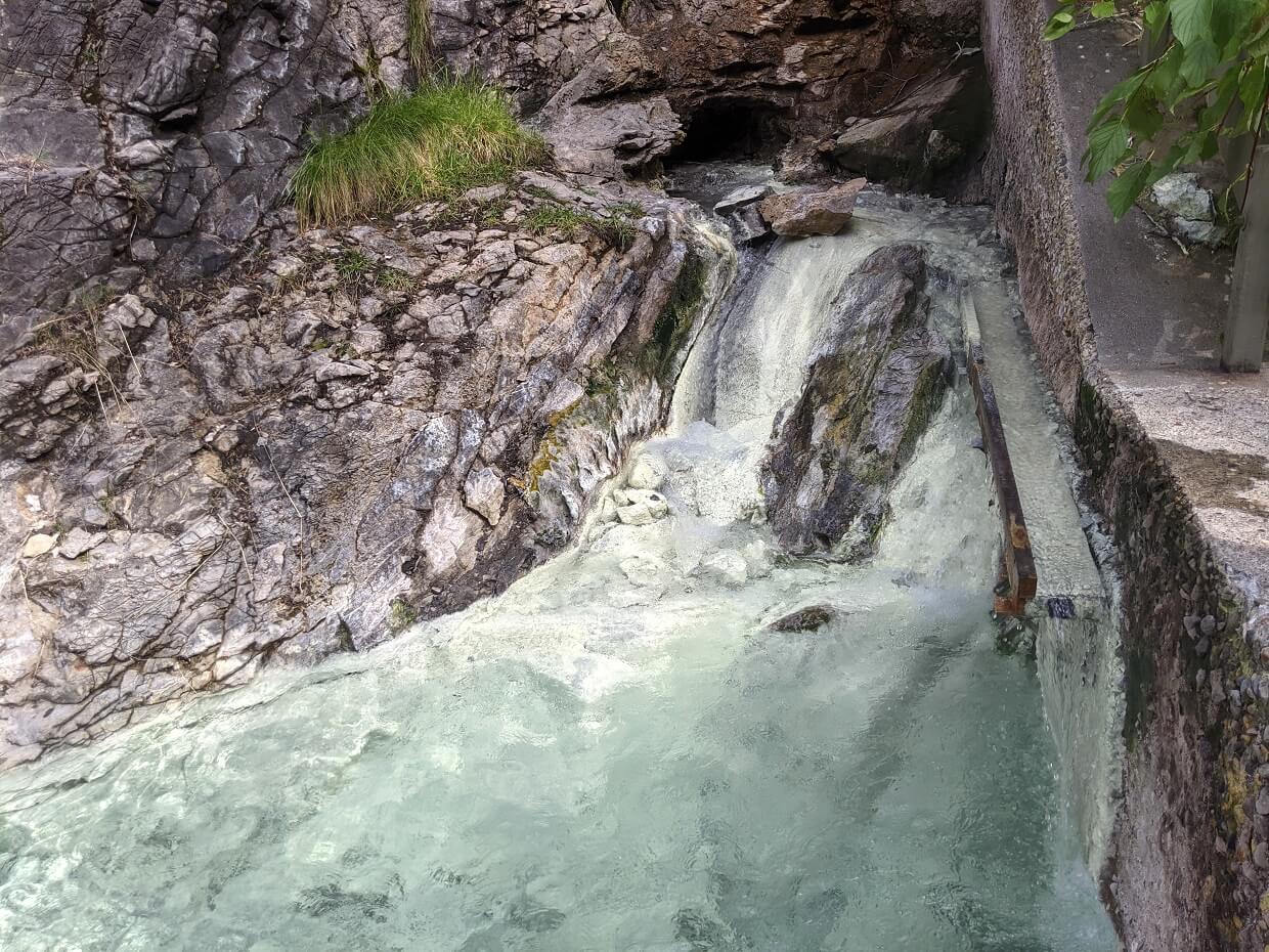 Front view of rushing stream flowing from cave at Miette Hot Springs source