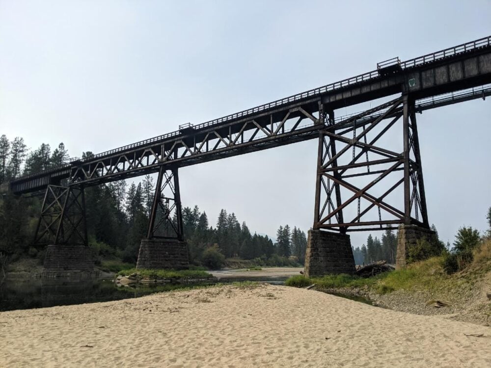 Looking up to a large railway trestle above a river and sand bank
