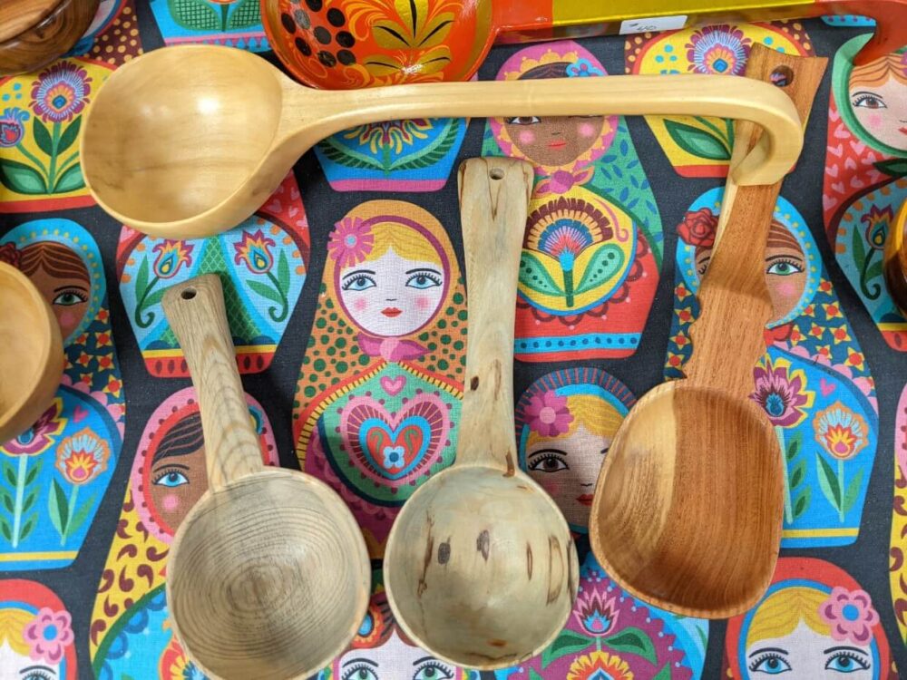 Overhead view of wooden spoons on top of colourful Russian doll tablecloth