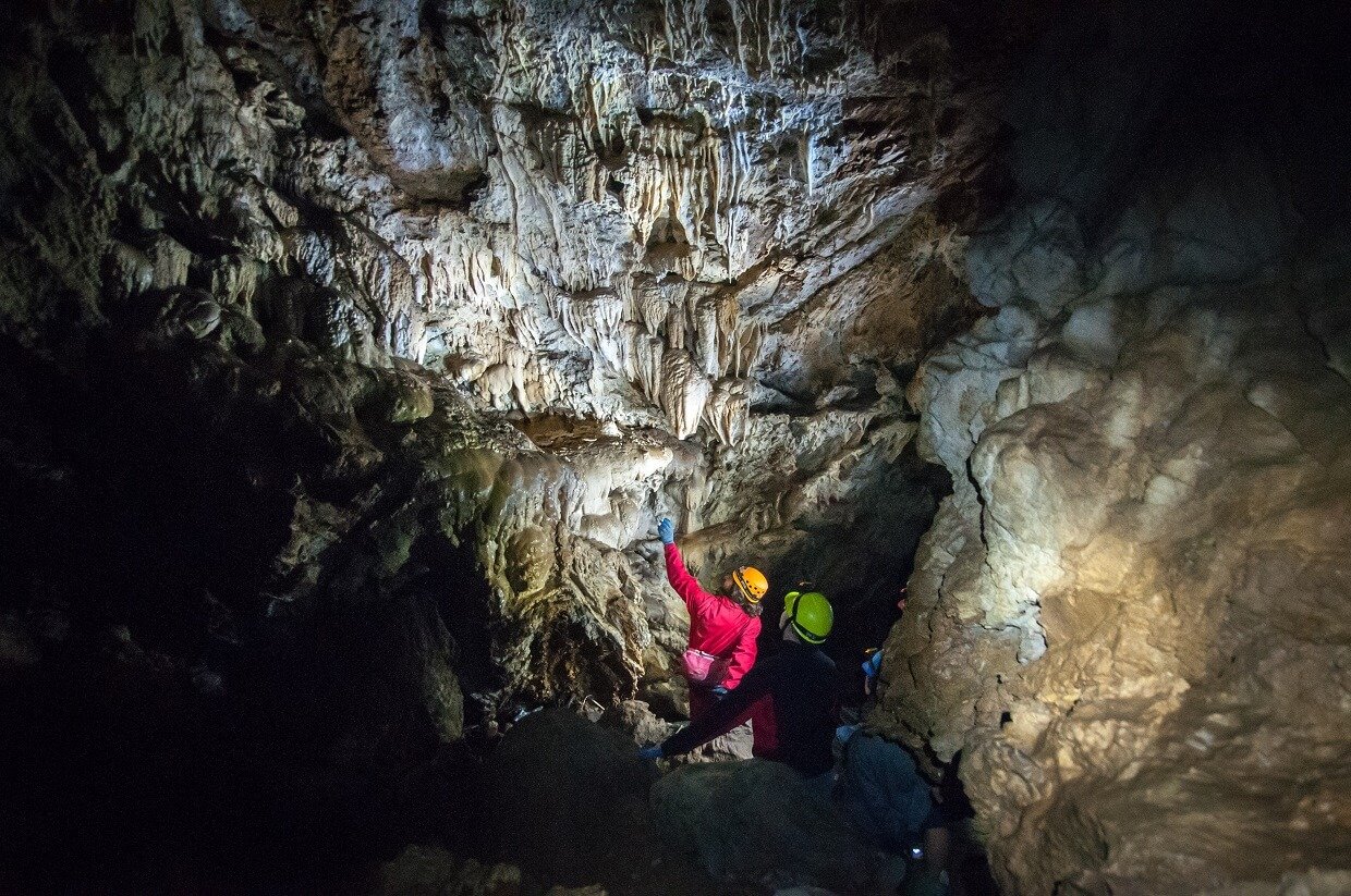 Lit up view of inside a cave with two people admiring formations