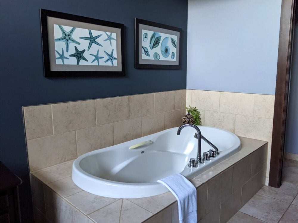 Large built in bathtub in Sunrise Ridge Waterfront Resort room, with framed pictures of starfish behind