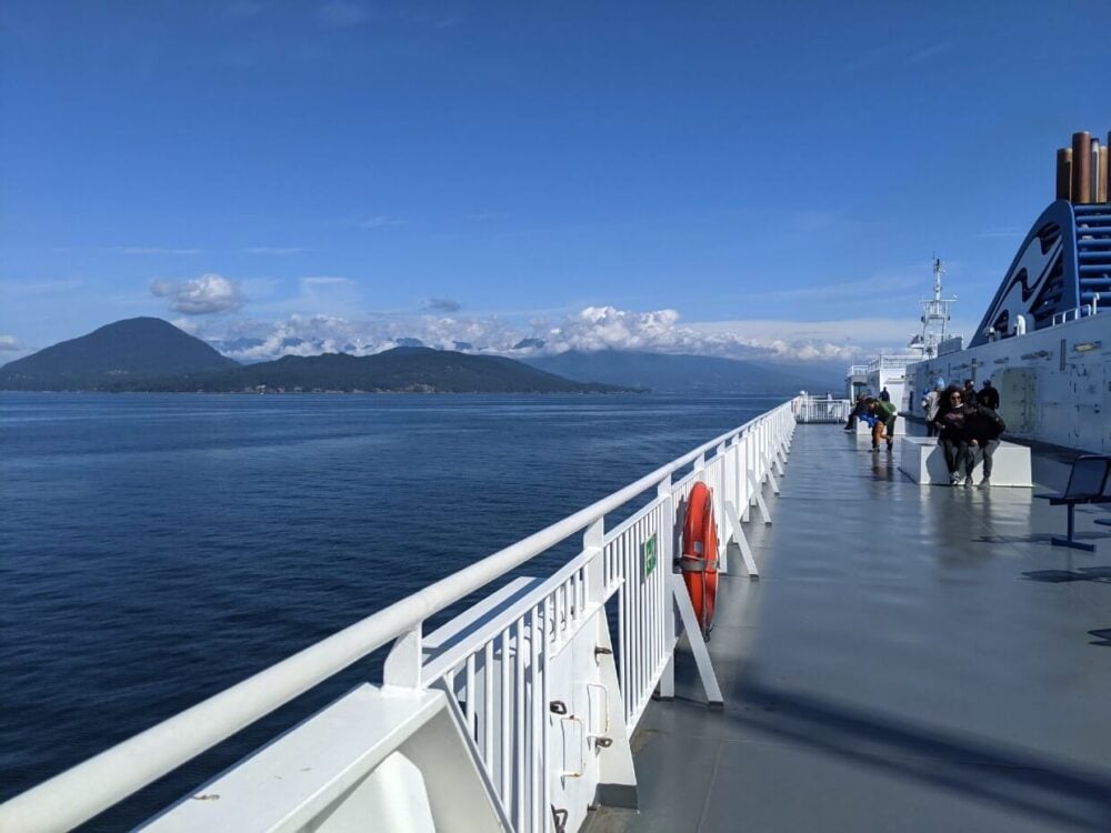 Sie view of BC Ferries deck with views of calm ocean and mountain behind