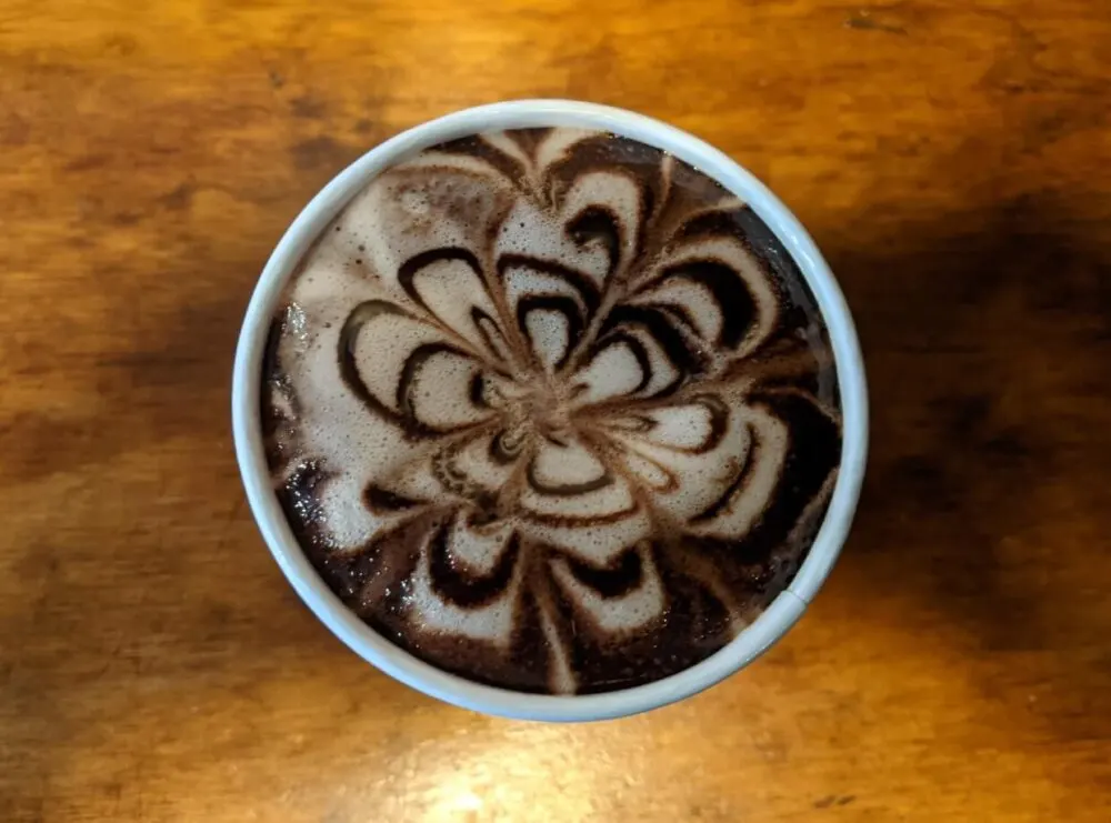 Overhead view of pretty flower pattern on hot chocolate at JoJos cafe