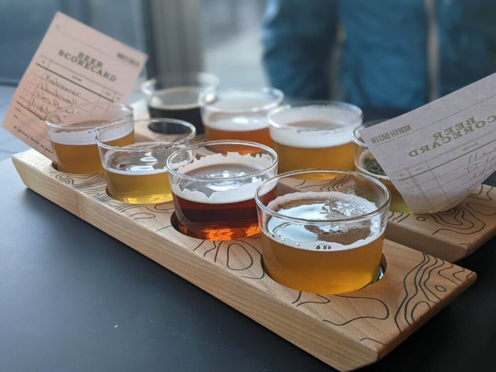 Close up of two flights of beer, with eight total glasses, each with a differently coloured beer