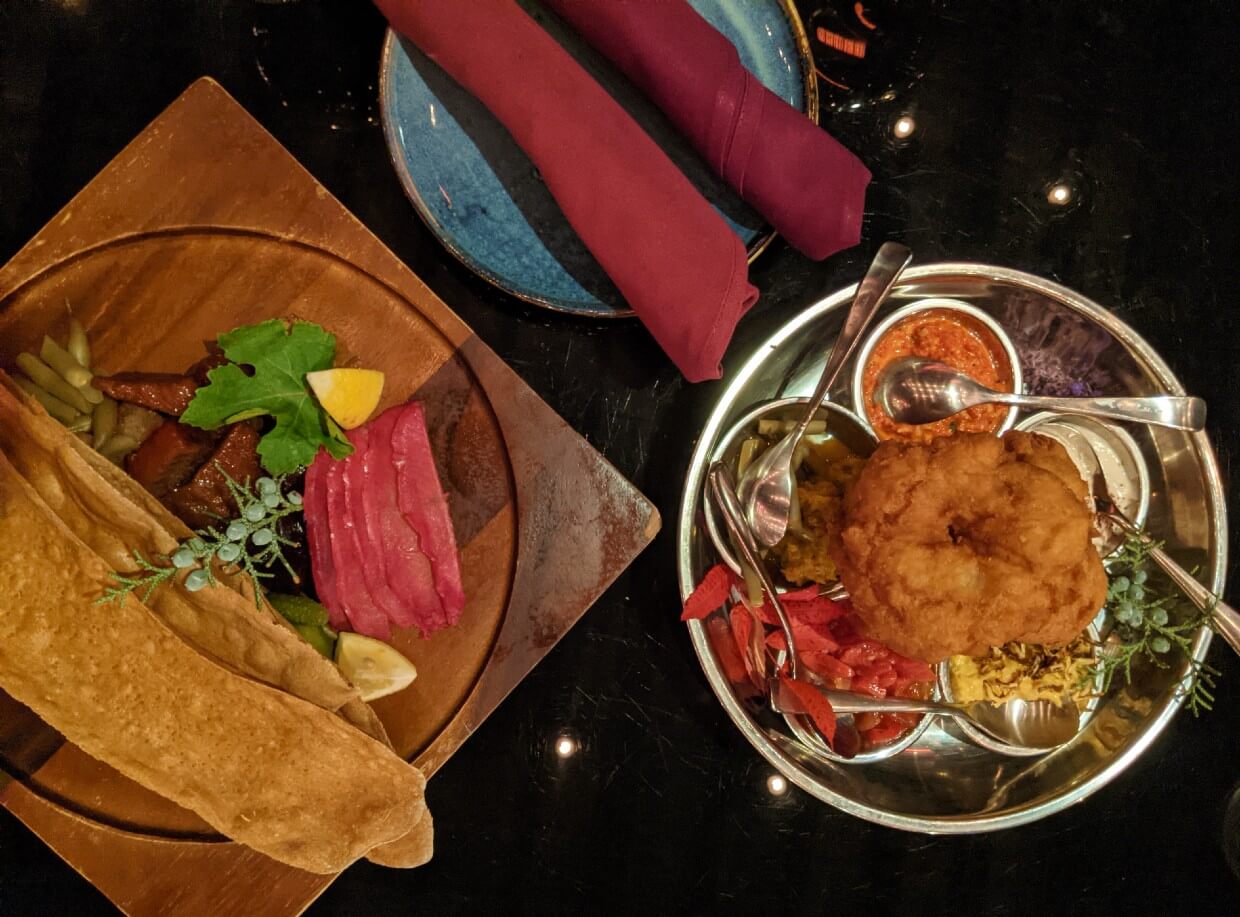 Overhead view of shared dishes at The Bear, the Fish, the Root & The Berry, with plate and napkins