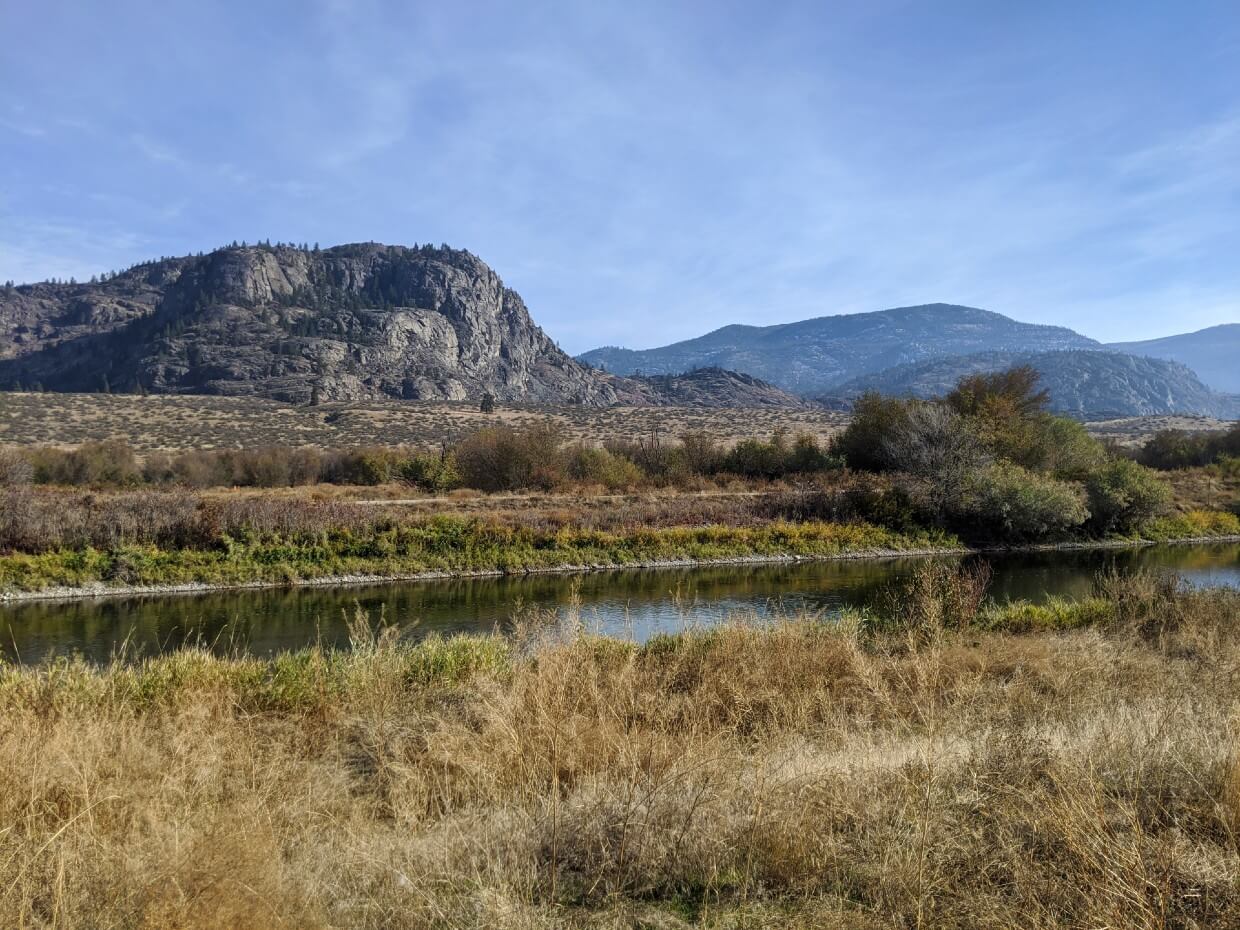 View looking across canal towards rugged desert and rugged hill scenery on Oxbows Trail