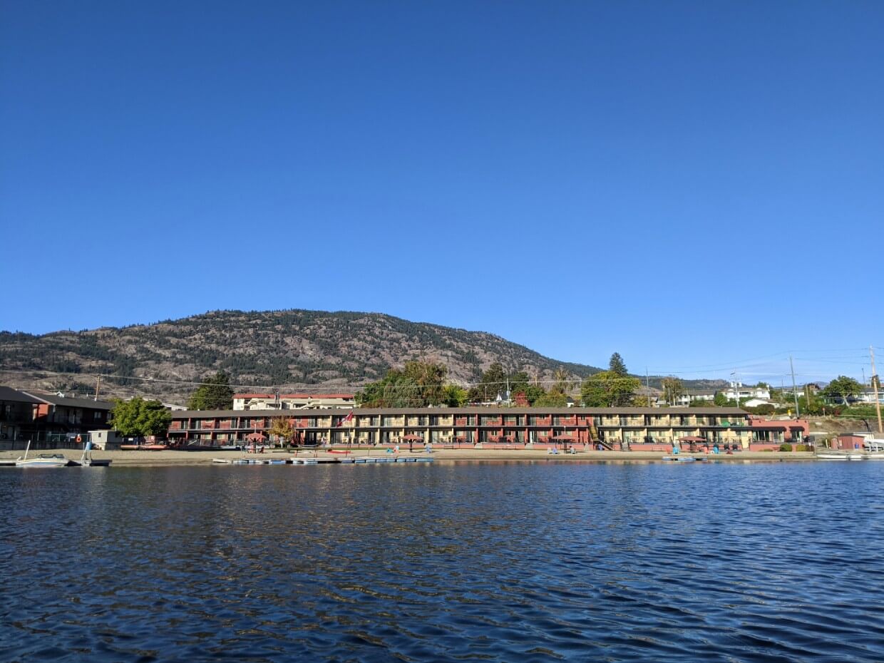 Looking across lake towards two story Safari Beach Resort on shore with private beach