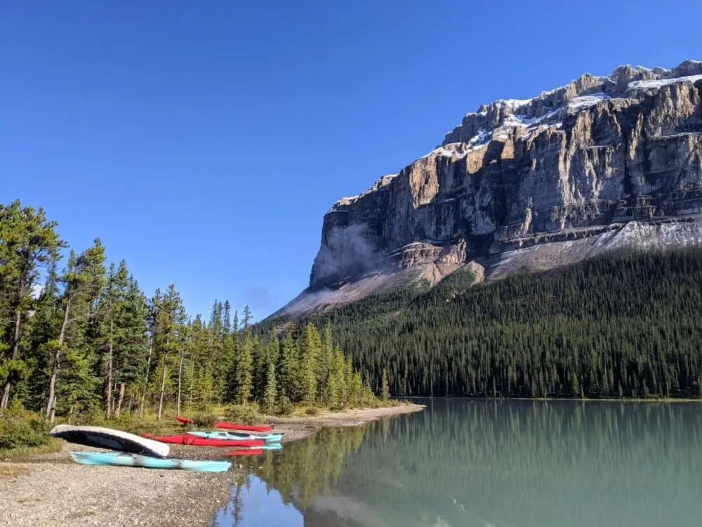 Coronet Campground beach with canoes and kayaks on shore, a huge mountain behind