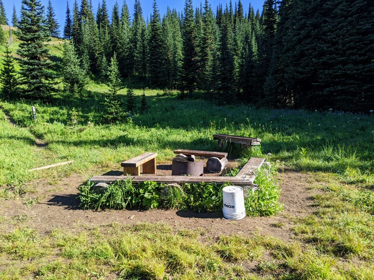 Fire pit and wooden seating at Deer Camp, surrounded by meadows