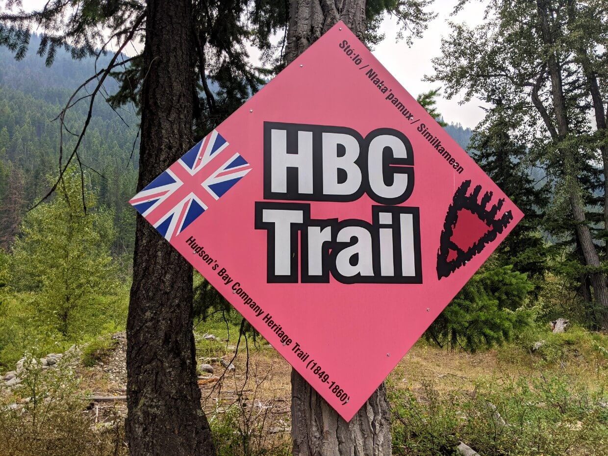 Close up of large red diamond shaped HBC Trail sign on tree