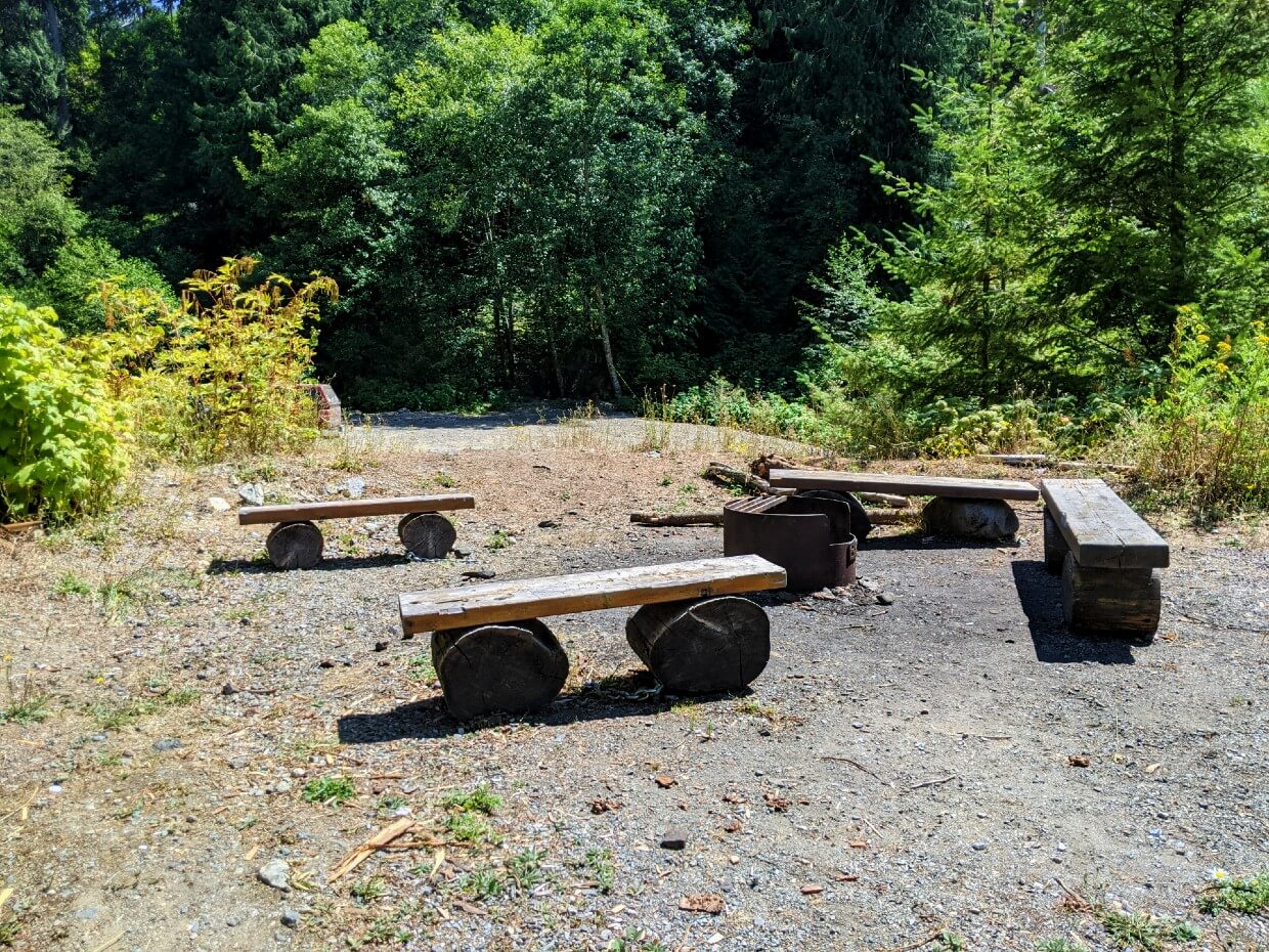 Circle of wooden bench seating around metal fire pit at Peers Creek trailhead