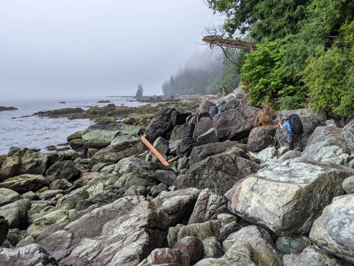 Hikers traversing huge boulders (some the size of small cars) on the coastal section between Thrasher Cove and Owen Point