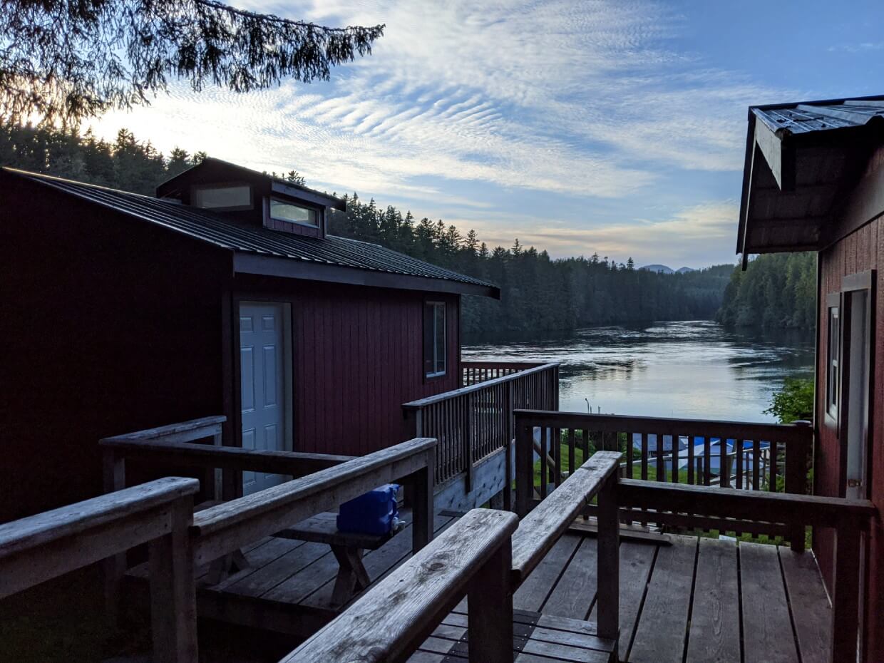 Sunset views at Nitinaht Narrows, looking between two wooden cabins towards lake