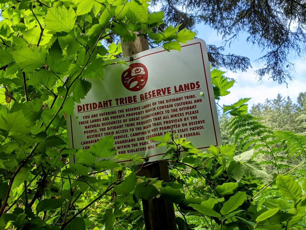 Close up of white Ditidaht Tribe Reserve Land sign, asking West Coast Trail hikers to stay on the established path