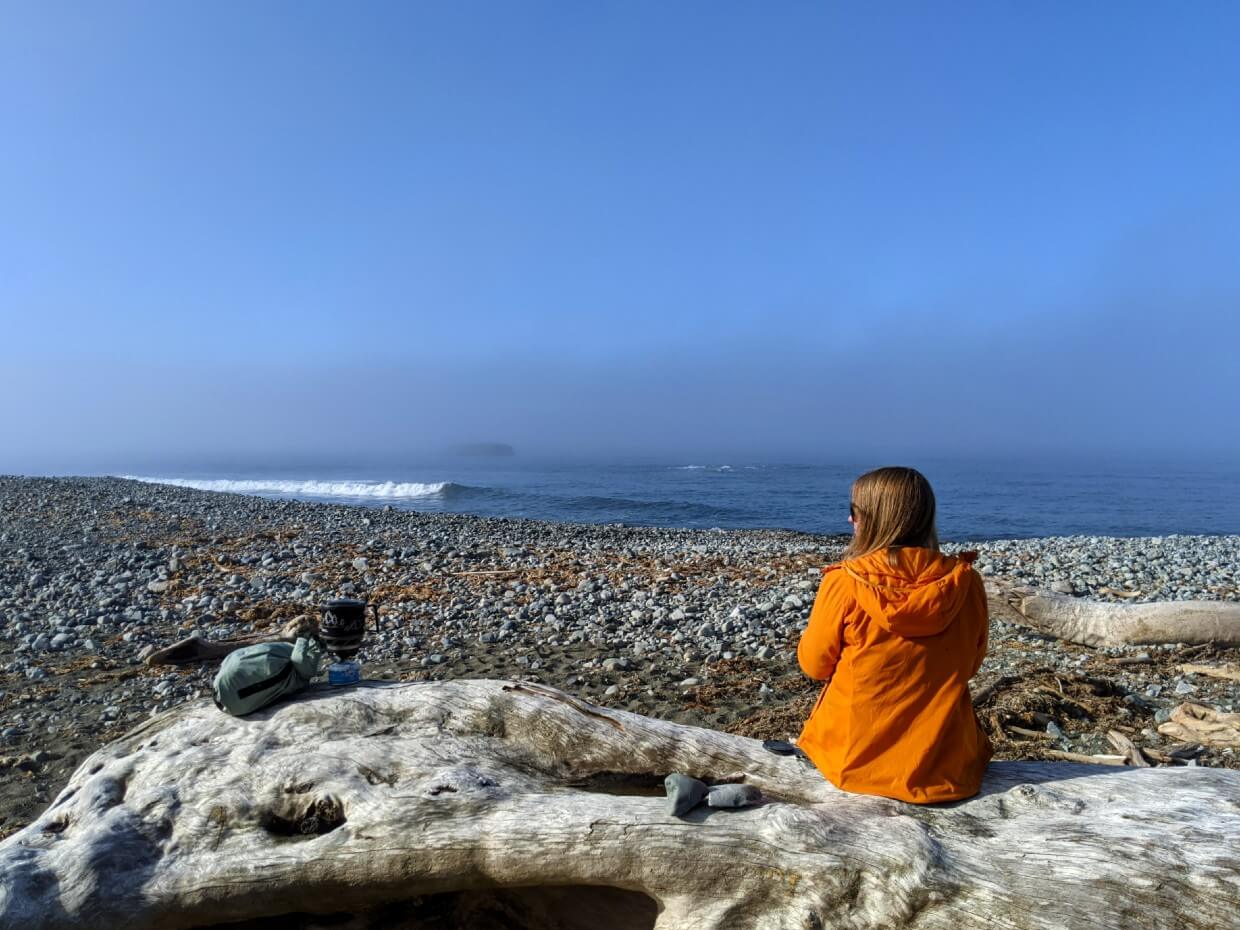 Back view of Gemma sat on driftwood log on Klanawa Beach