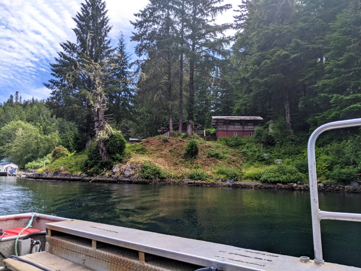 Looking up from Nitinaht Narrows ferry towards elevated cabin on shore