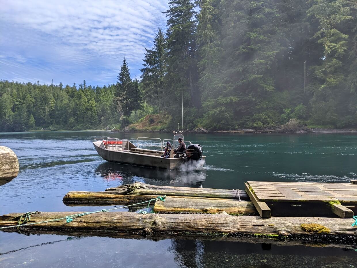 A boat powers away from a wooden dock at Nitinaht Narrows on the West Oast Trail