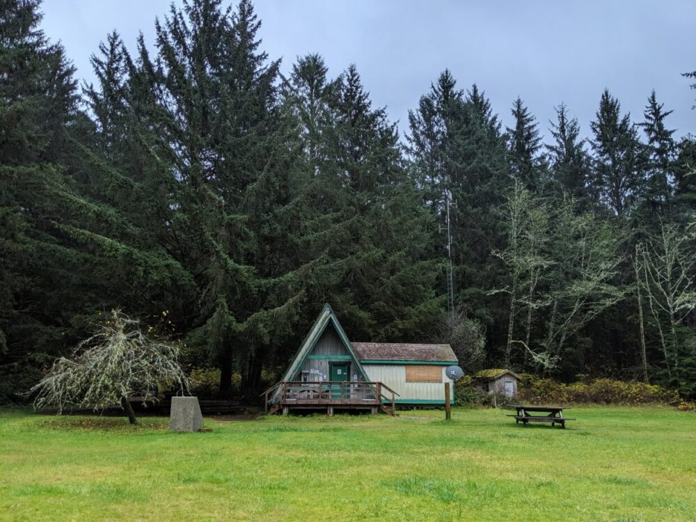 Green lawn in front of a frame Parks Canada office at Pachena Bay, surrounded by forest