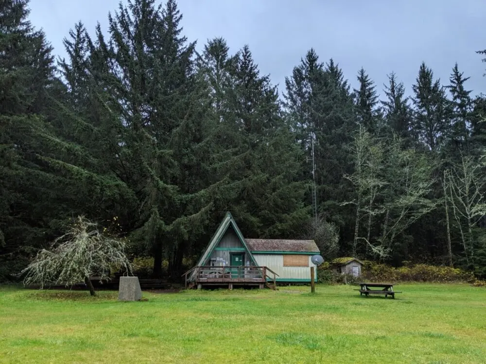 Green lawn in front of a frame Parks Canada office at Pachena Bay, surrounded by forest