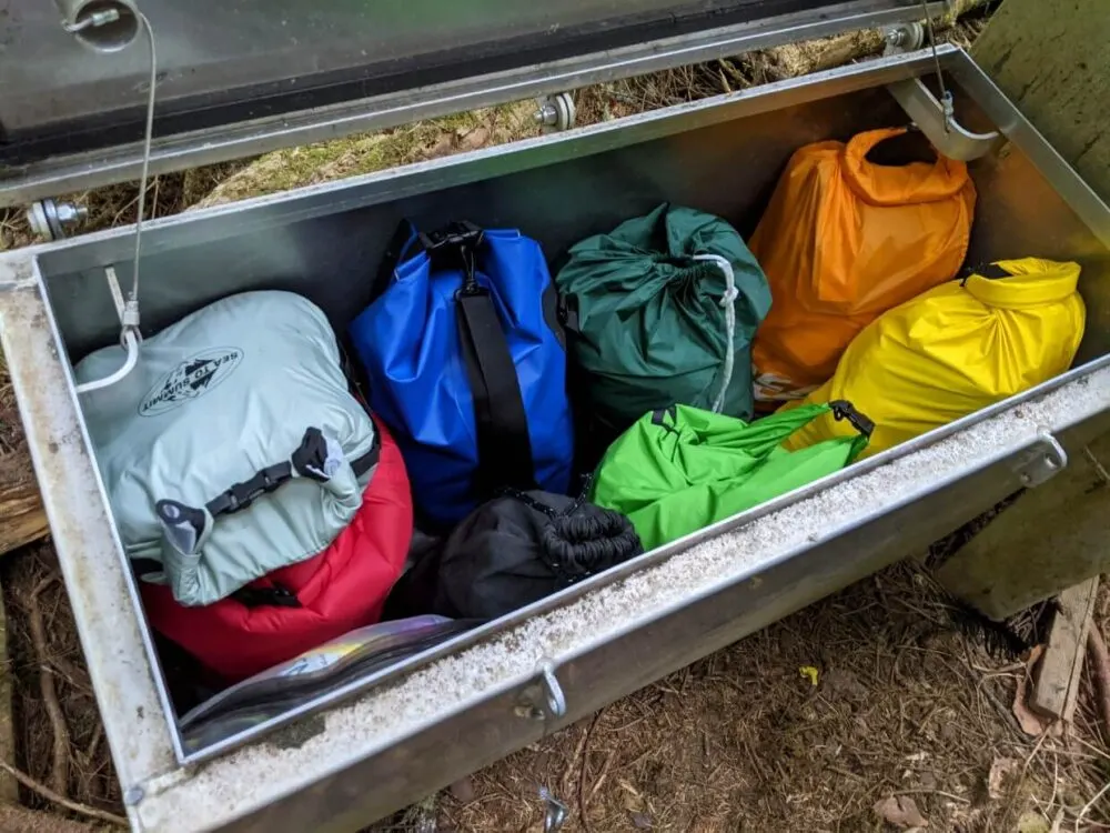 Looking into metal bear cache with eight colourful dry bags visible in box