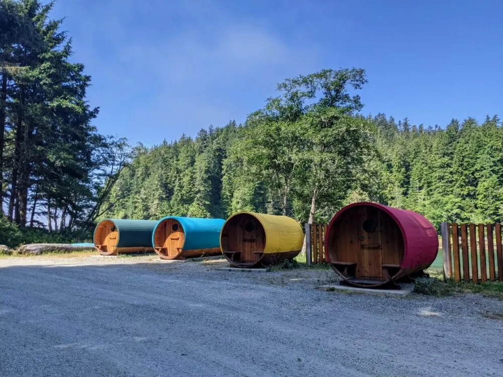 Four colourful barrel shaped cabins in front of forest