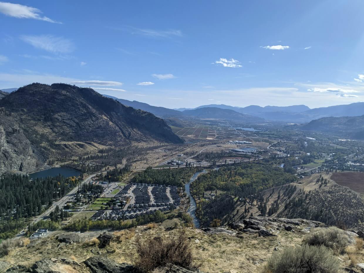 Elevated view from McIntyre Bluff (nʕaylintn) looking down on sun drenched south Okanagan landscape with brown hills and vineyards
