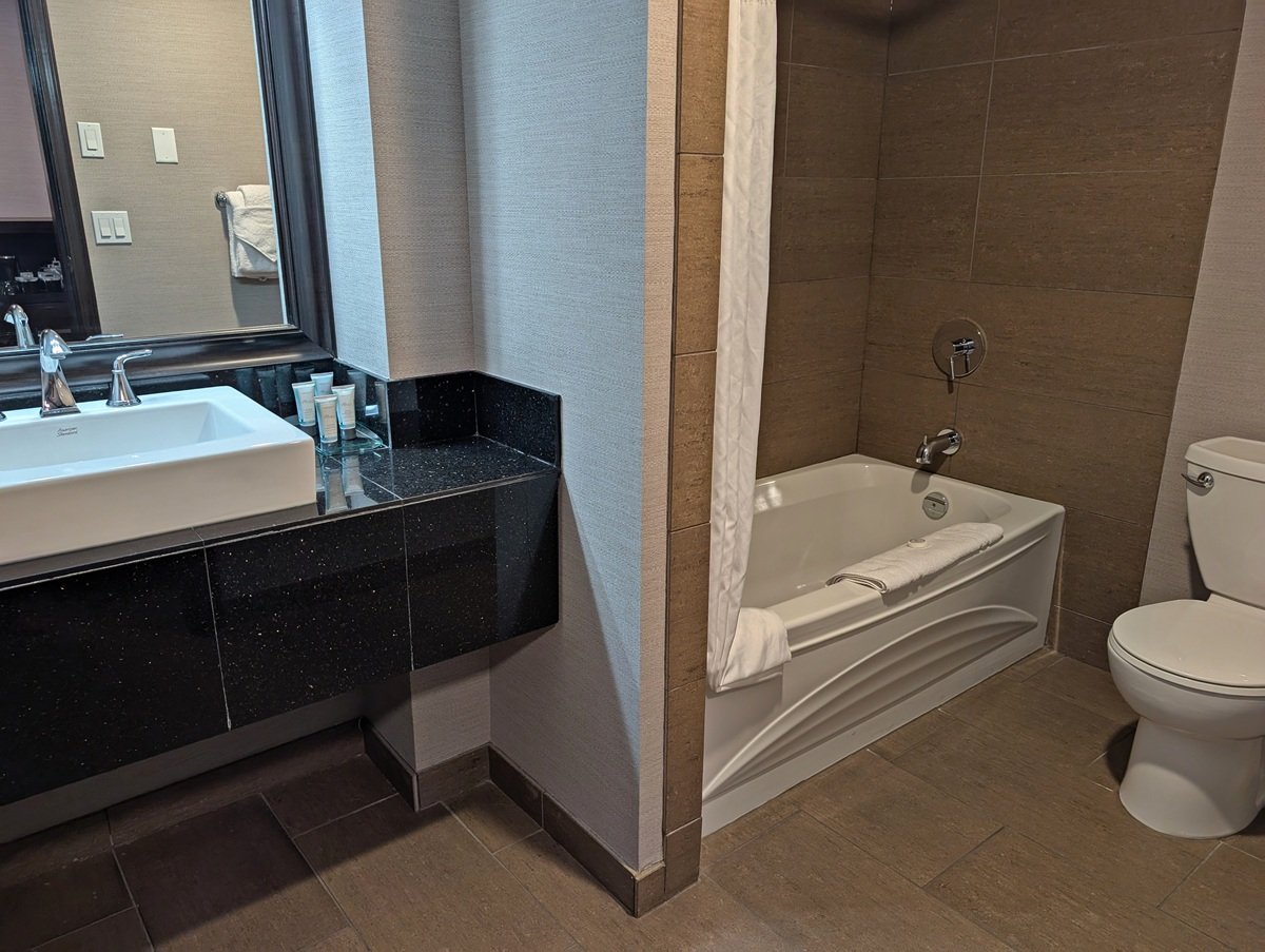 Side view of Prestige Hotel bathroom with bathroom, black counter and deep sink