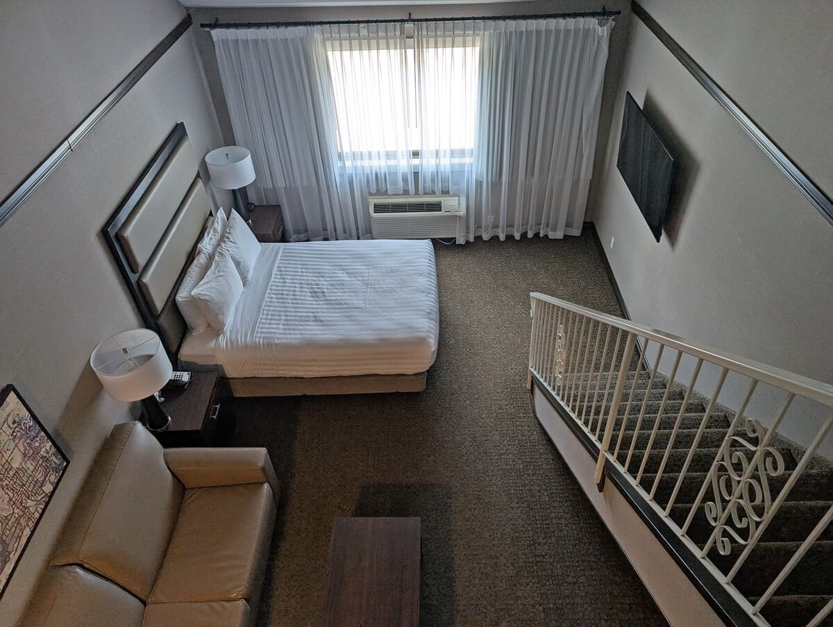 Looking down from mezzanine level to main bedroom area at Prestige Hotel Vernon, with queen bed and sofa bed next to window 