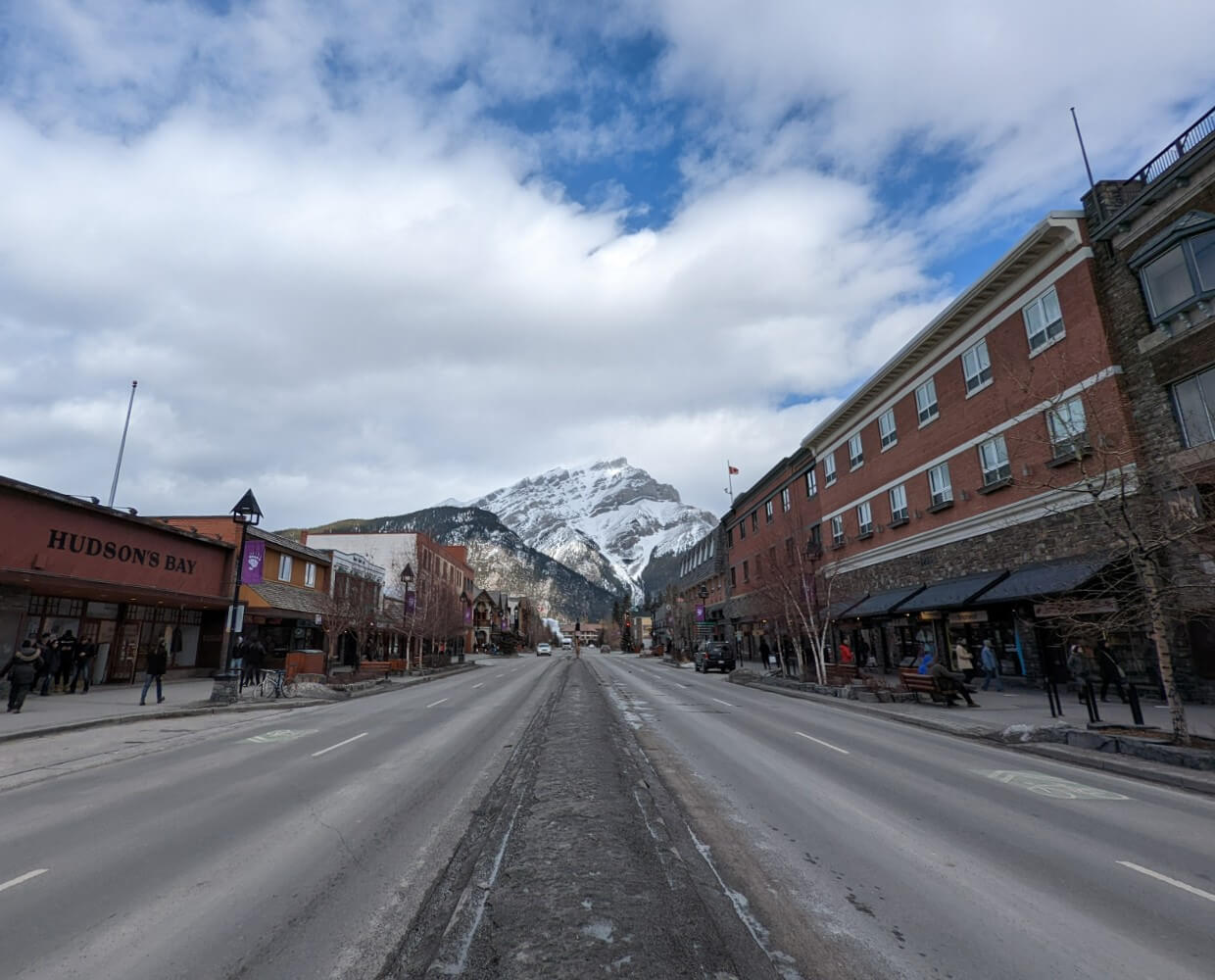 Street view looking up at Cascade Mountain behind the shops and stores of downtown Banff