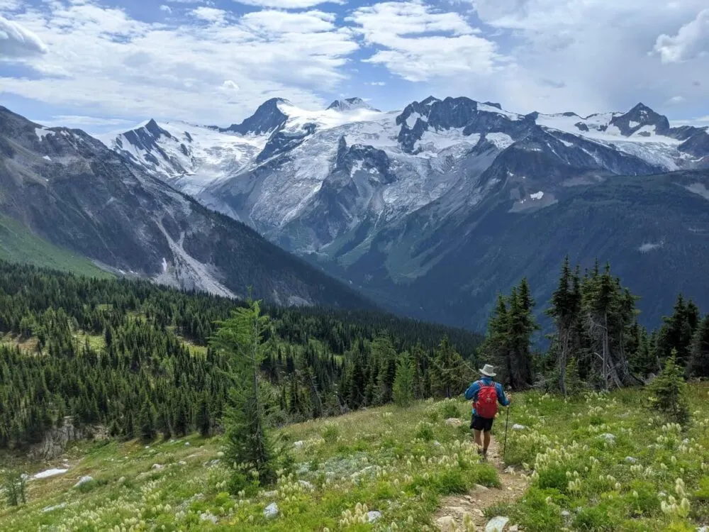 Back view of JR walking down hiking path with huge snow capped mountains and glaciers in background