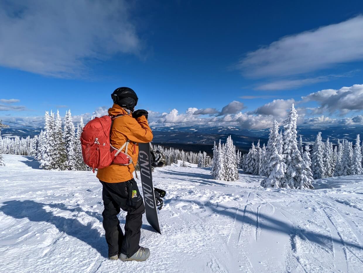 Back view of JR with snowboard looking out over Monashee Mountains at SilverStar Mountain Resort