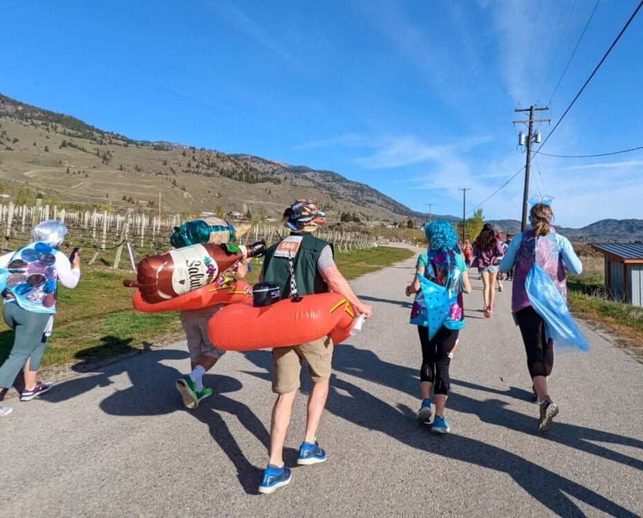 Back view of runners at Half Corked Marathon, some wearing fish costumes and others wearing inflatable dinghies with fishing rods