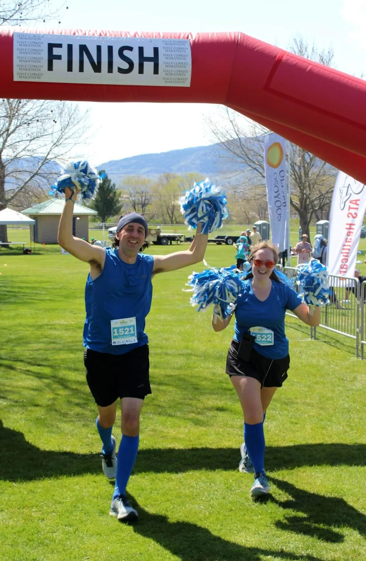 Front view of Gemma and Ricky approaching finish line at Half Corked Marathon, dressed as cheerleaders