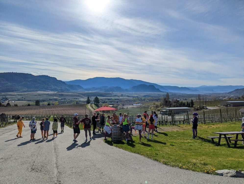 Runners standing by tasting bar outside Road 13 Winery, with views of southern Okanagan Valley vineyards and mountains