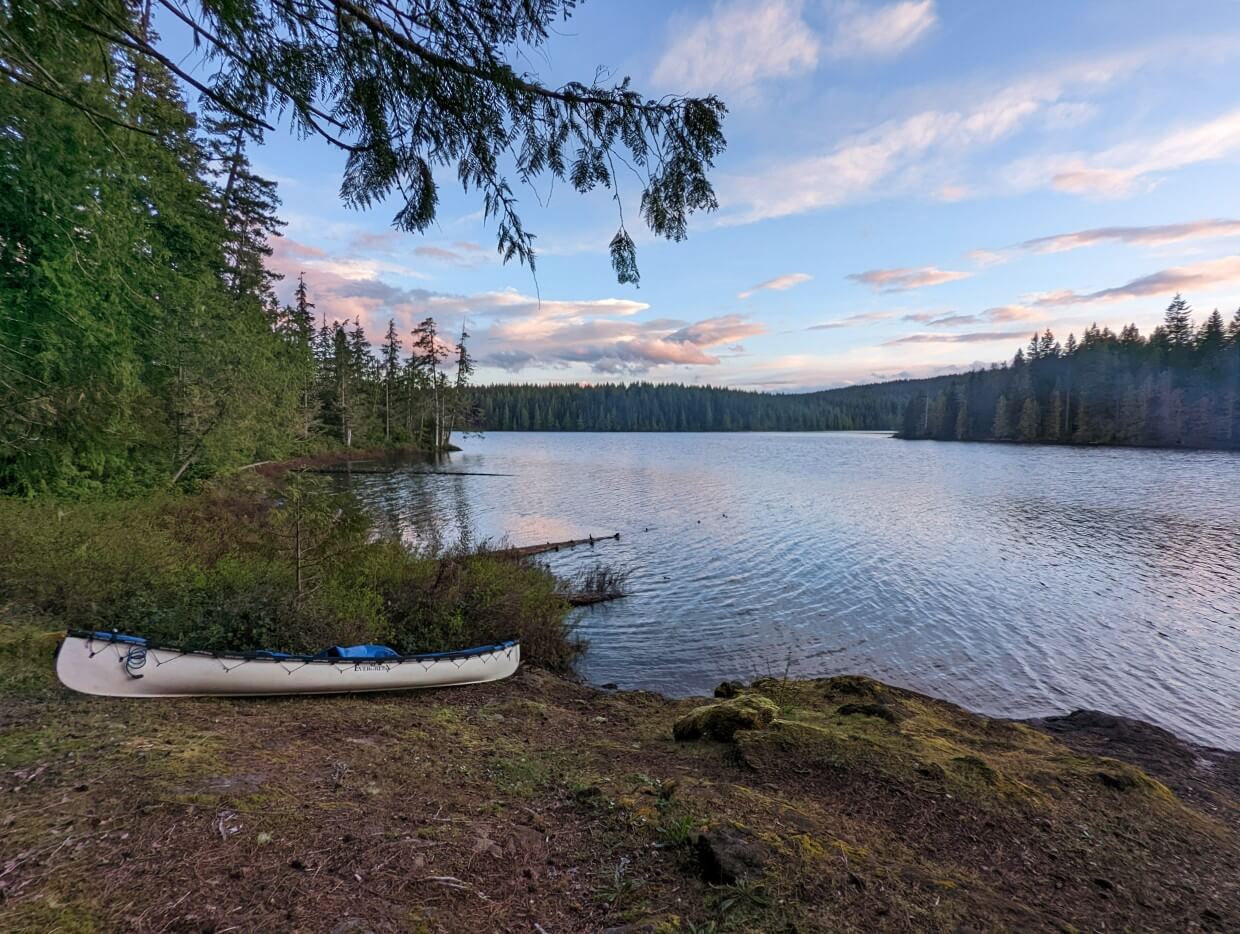Canoe resting on shore of island on Sayward Forest Canoe Circuit, one of the best BC canoe trips. There are sunset colours in the sky