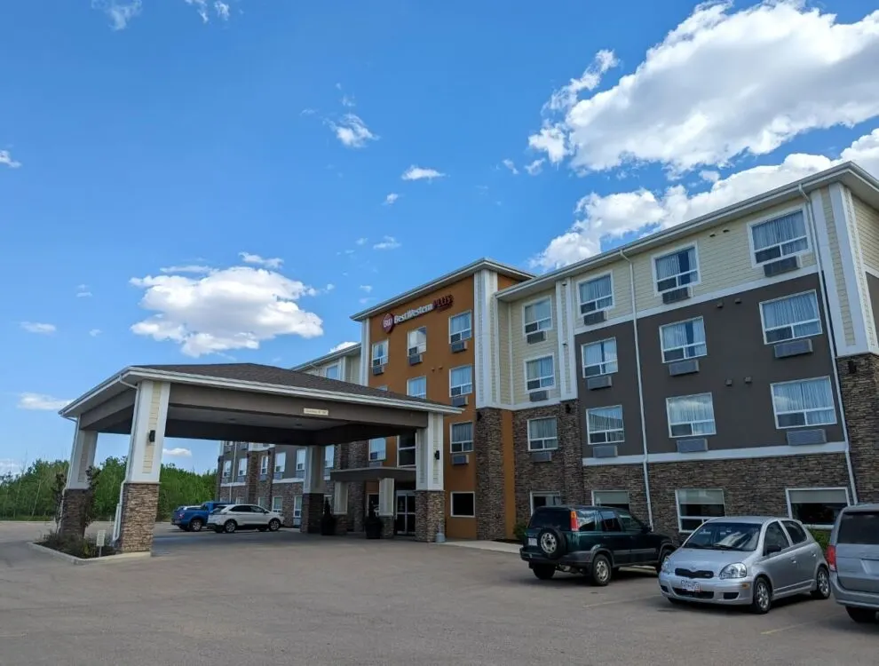 Exterior view of Best Western Plus hotel in Lacombe - four story building with high entrance foyer and parked cars