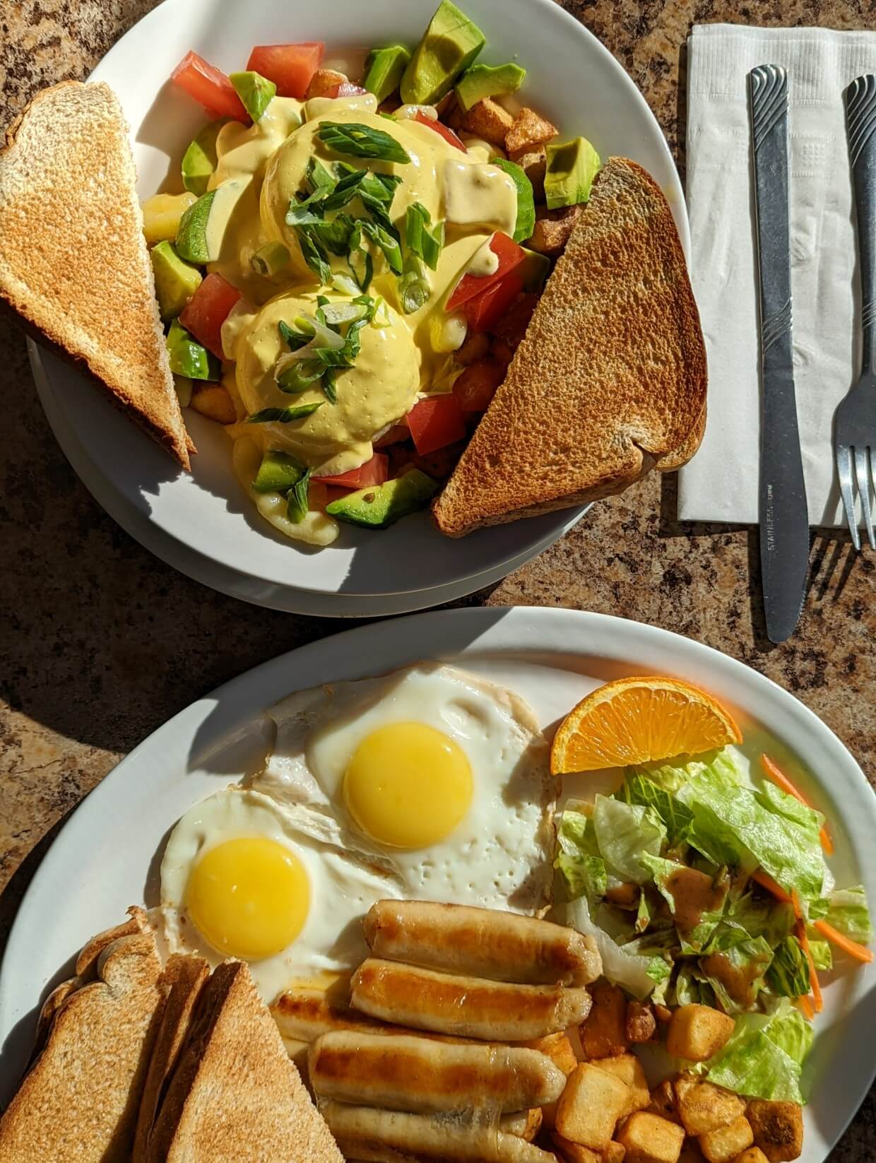 Overhead view of breakfast dishes at Brunch Glory, both featuring toast and eggs on white plates