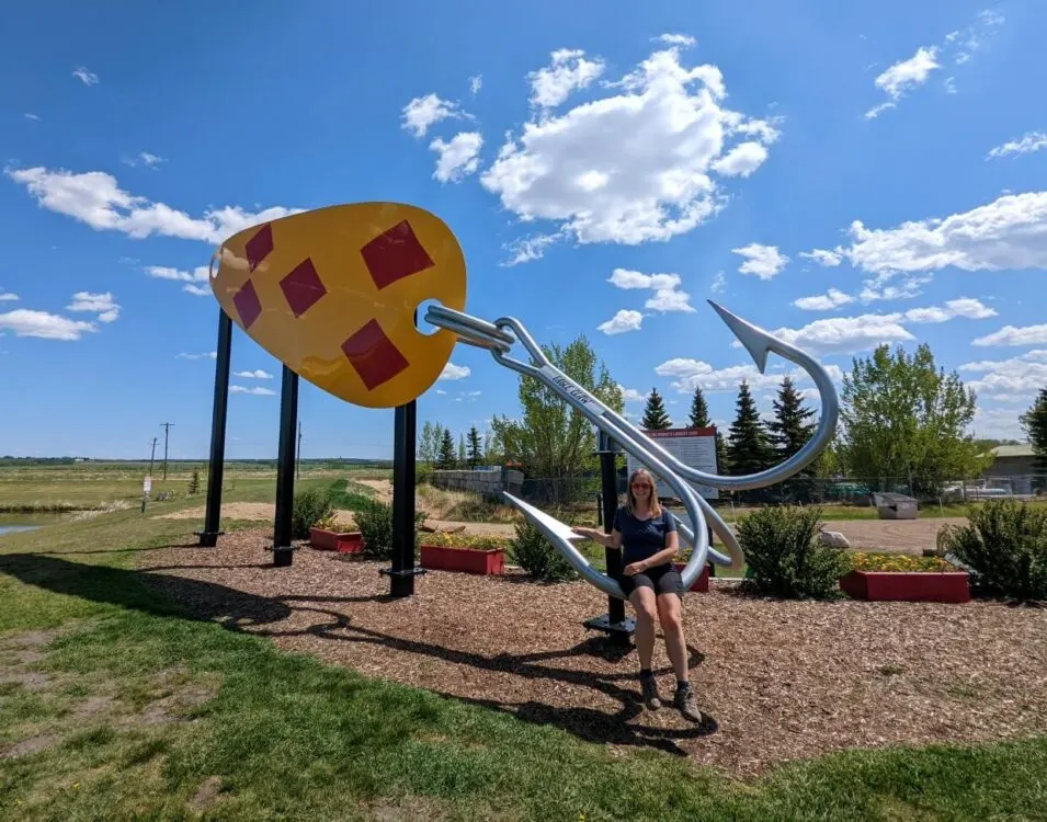 Gemma sits on the hook of the world's largest fishing lure, one of the best things to do in Lacombe