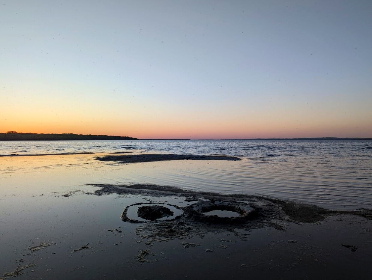 Sunset on Gull Lake near Lacombe, with orange colours visible near horizon over sand