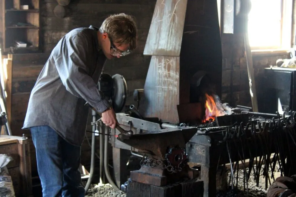 Close up of blacksmith working at the Lacombe Blacksmith Shop Museum. A forge is burning in the background