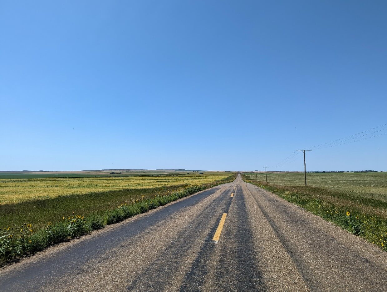 Driving view of road heading to Grasslands National Park, surrounded by grain fields