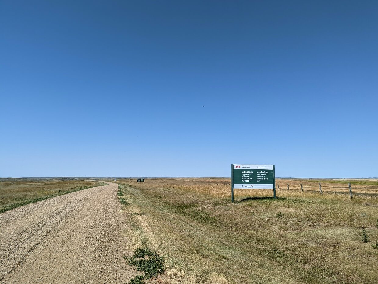 Gravel road leading past Grasslands National Park signage