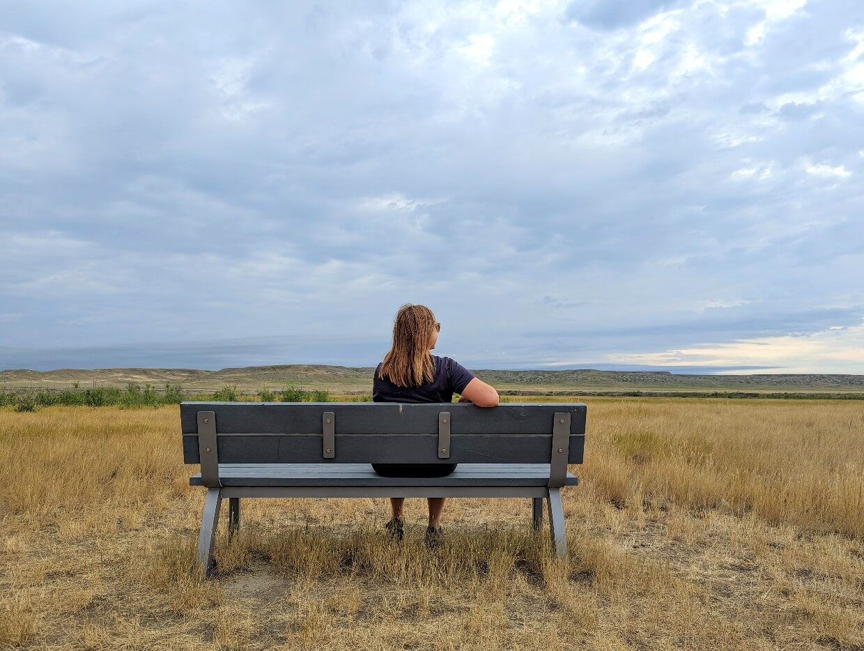 Back view of Gemma sat on bench in the West Block of Grasslands National Park, looking out to the scenery