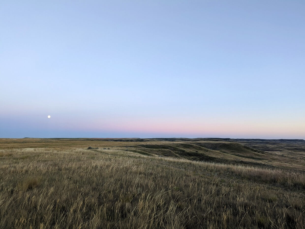 Looking across calming Grasslands scenery at sunset with rising moon in background