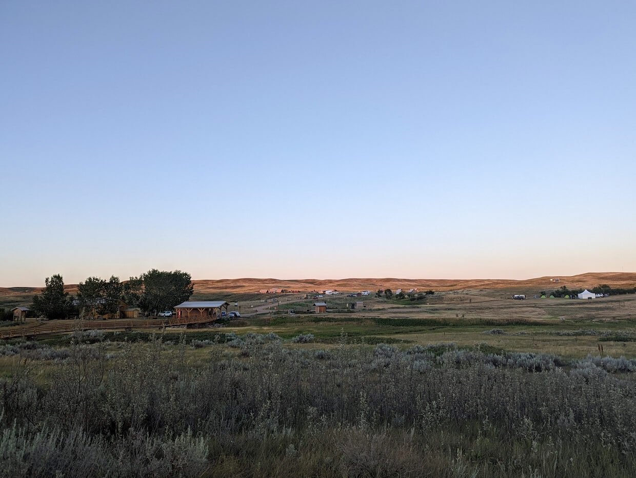 Looking across grasslands towards Rock Creek Campground, where a number of cars and RVs are parked
