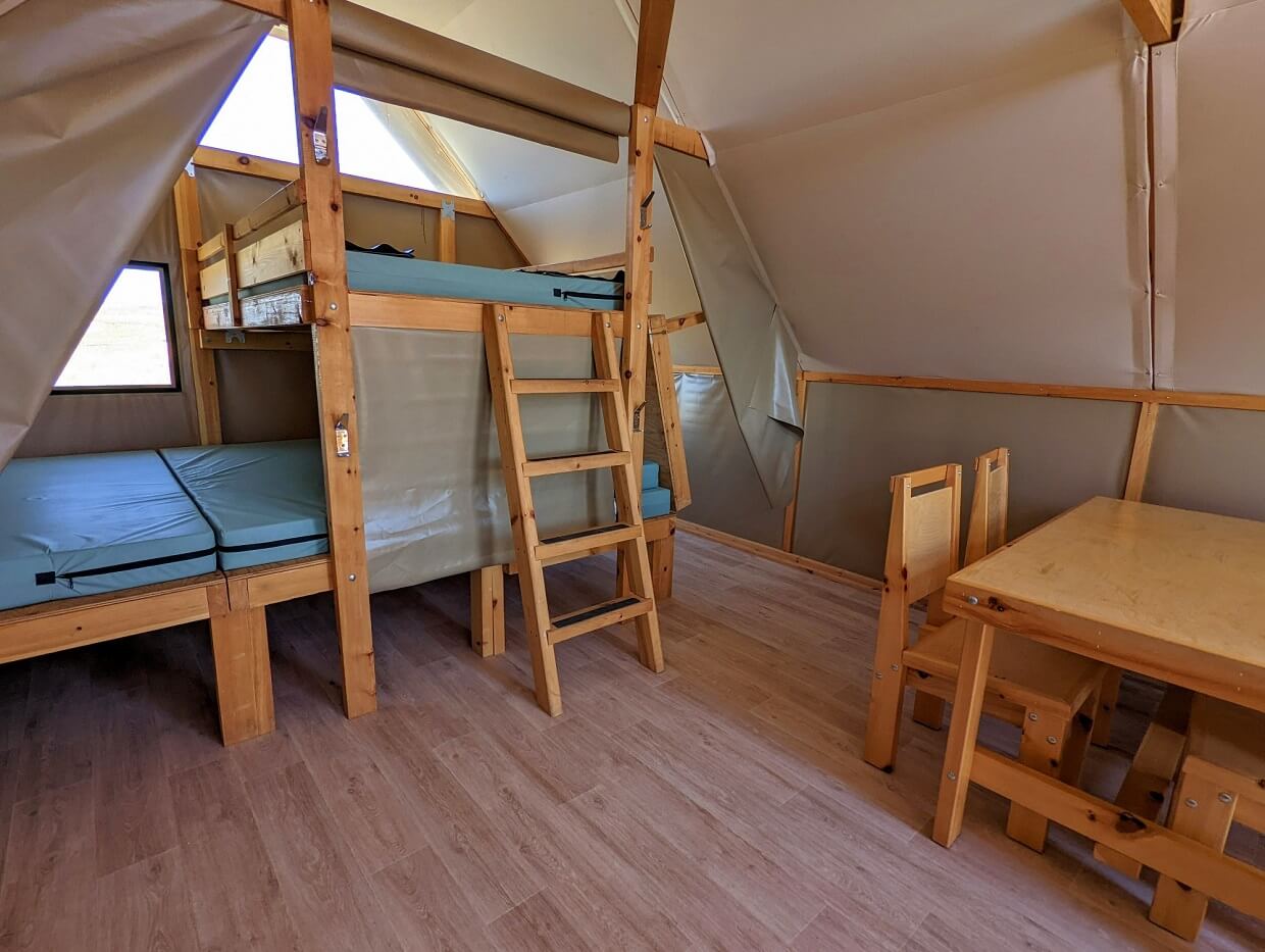 Interior view of oTENTik with double layer sleeping area with table and chairs close to camera