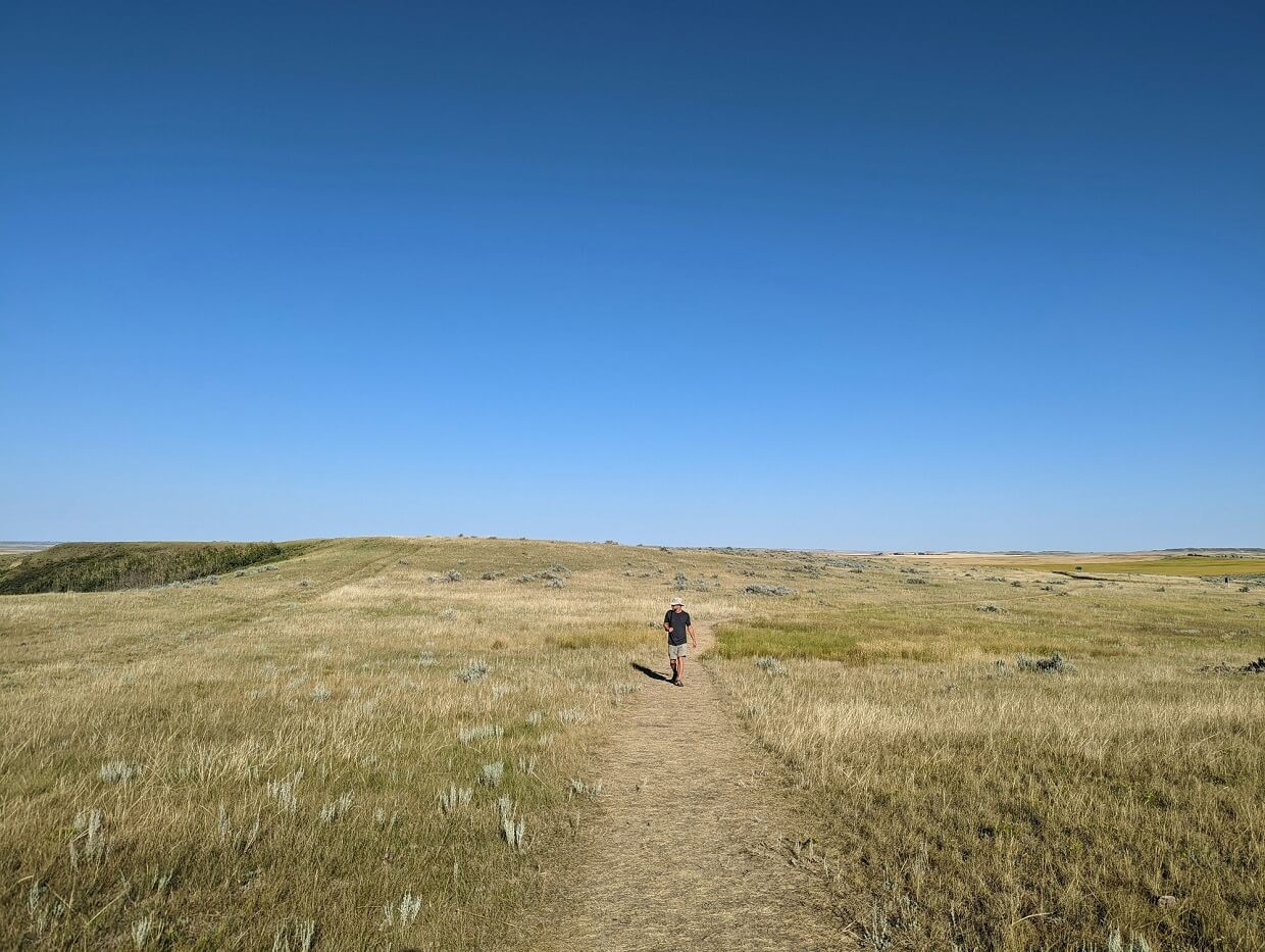 Front view of JR walking towards camera on hiking trail through grasslands scenery
